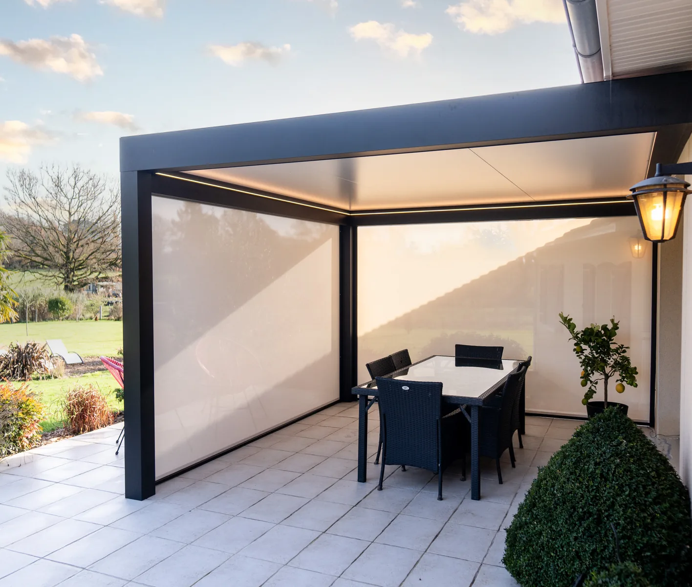 Pérgola adosada de aluminio Lily Kostum equipada con cortinas zip blancas